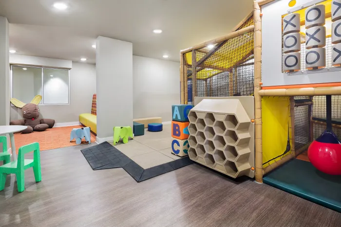 Bright and inviting playroom with colorful chairs, soft toys, and a playful climbing structure perfect for children's activities.