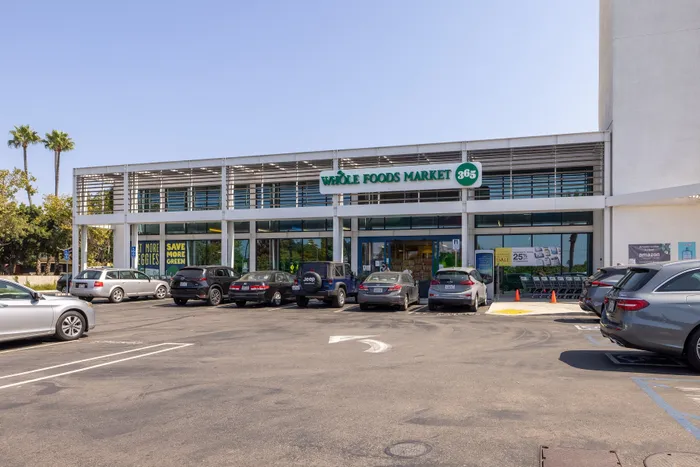 Inviting Whole Foods Market entrance with ample parking and vibrant signage, offering a convenient and fresh shopping experience.