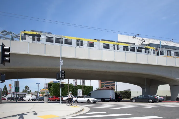 Modern urban scene featuring a sleek Metro Rail train traversing an elevated track with bustling city streets below, capturing the essence of city life and convenience.
