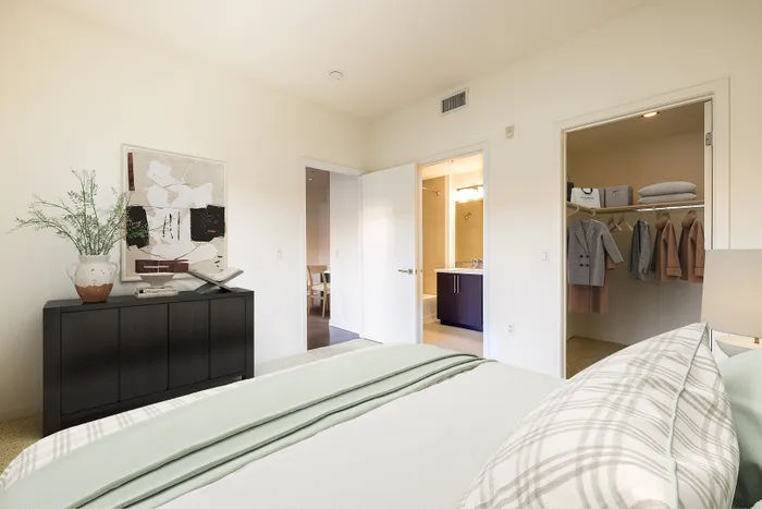Sawtelle, CA, Luxury Apartments with In-Unit Washer and Dryer - C on Pico - Bedroom with a Cozy Bed, Stylish Decor, Dresser, Spacious Oversized Closet, and Doorway to the Bathroom.