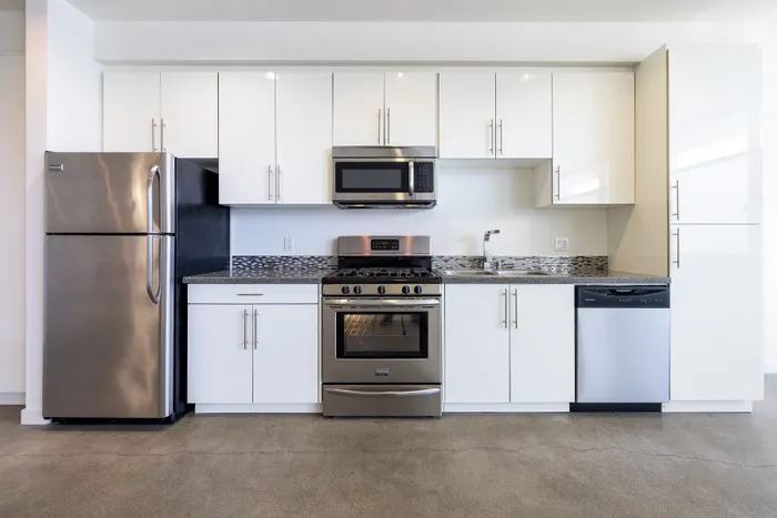 Modern kitchen with sleek white cabinetry, stainless steel appliances, and elegant backsplash. Perfect for gourmet cooking.