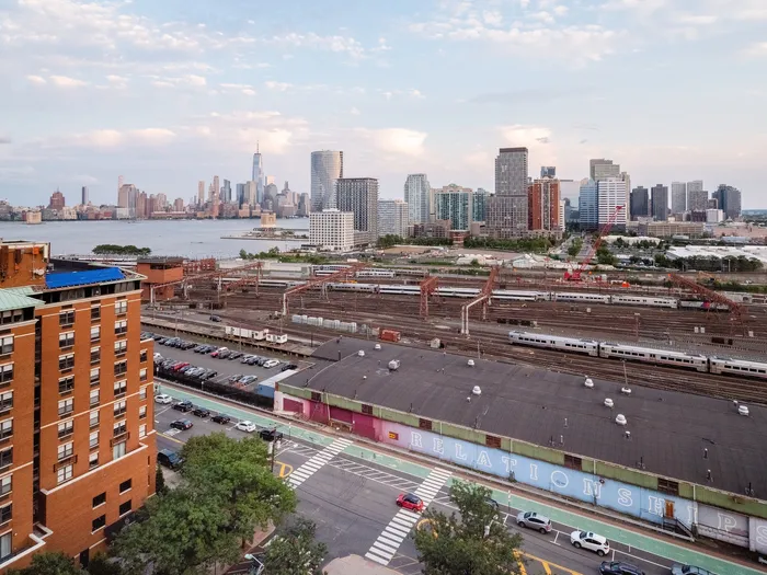 Stunning urban view featuring vibrant cityscape, high-rise buildings, and expansive rail yard with trains, ideal for city lovers seeking modern living.