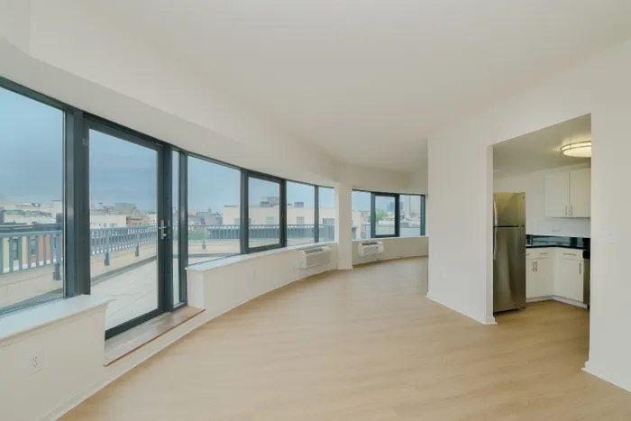 Bright and modern open-plan apartment with expansive windows, sleek kitchen, and cityscape views.