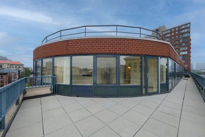 Chic rooftop circular apartment with expansive glass windows and private terrace offering stunning city views.