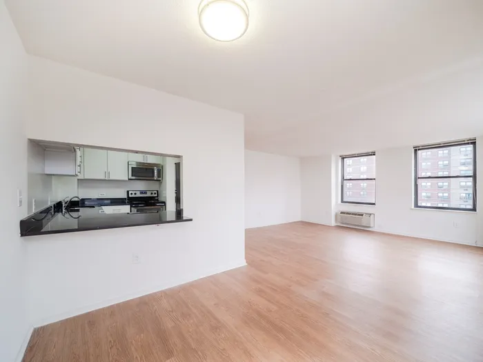 Bright and spacious modern apartment with open living area, hardwood floors, and sleek kitchen featuring stainless steel appliances.