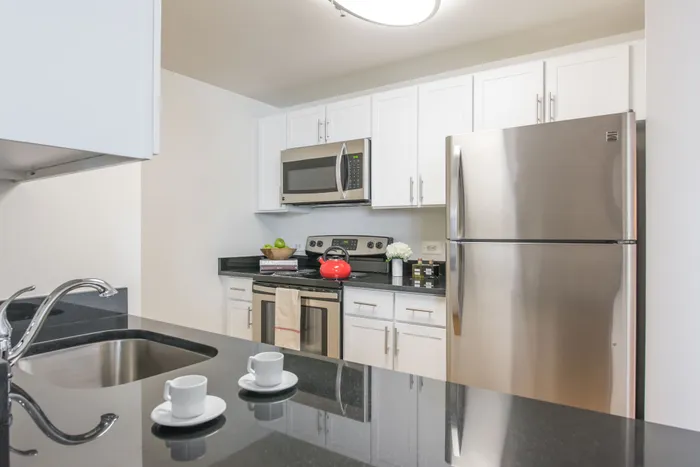 Pet-Friendly Luxury Apartments In Hoboken, NJ - 77 Park Avenue - A Clean, Modern Kitchen With White Cabinetry, Black Granite Countertops, And Stainless Steel Appliances.