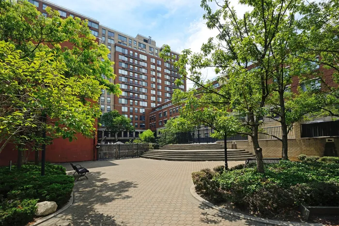 Charming urban courtyard featuring lush greenery and a modern apartment building, perfect for city living.