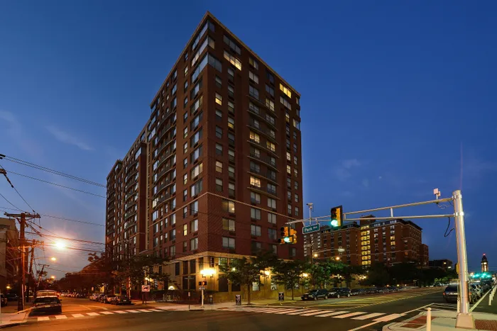Elegant and modern high-rise apartment building illuminated during twilight with inviting city street view.
