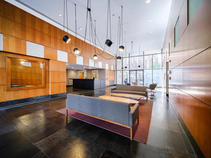 Modern and inviting apartment lobby featuring sleek design, comfortable seating, and abundant natural light from floor-to-ceiling windows.