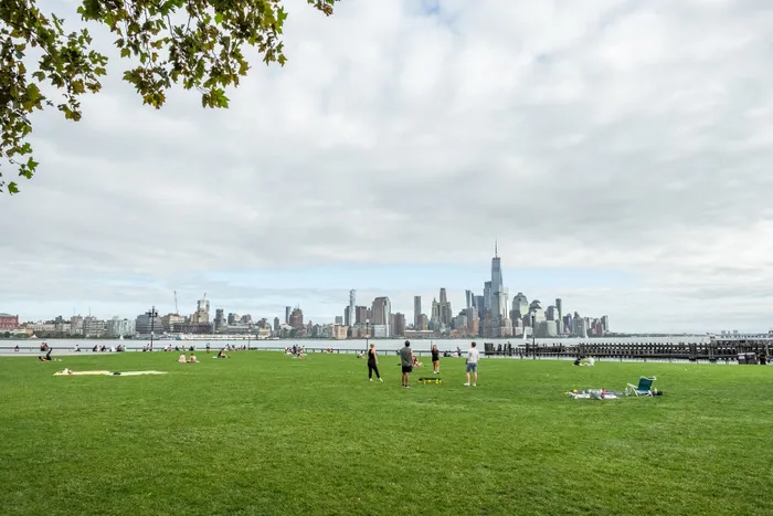 Vibrant park scene with lush green lawns and a stunning city skyline backdrop, offering a perfect blend of nature and urban living.