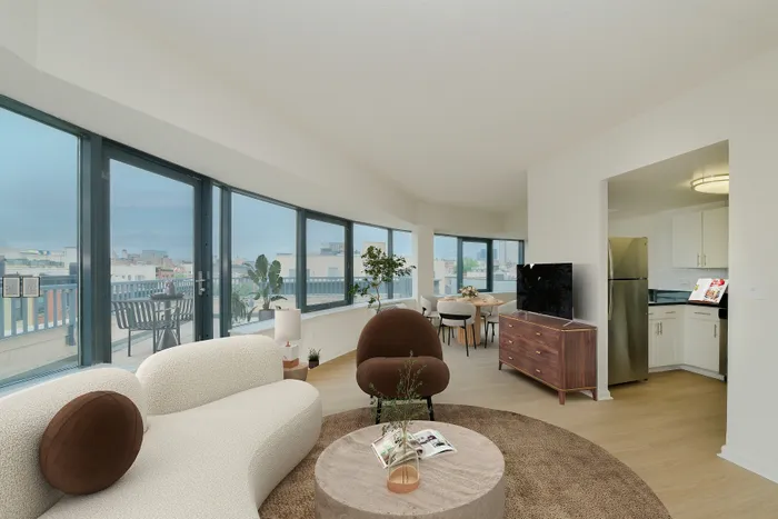 Bright, modern living space with panoramic city views, featuring cozy seating, a chic dining area, and sleek kitchen details.