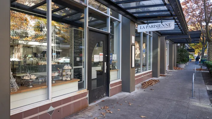 Charming exterior of La Parisienne French Bakery, showcasing stylish decor and inviting glass windows on a tree-lined street.