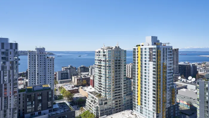 Breathtaking urban skyline featuring modern high-rise apartments with stunning ocean views and clear blue skies.