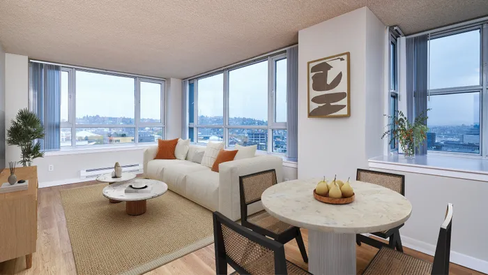 Dog-Friendly Luxury Apartments in Seattle, WA - Centennial Tower and Court - Living Area with White Couch, Coffee Tables, Media Console, Wall Art, Dining Table, Chairs, and Large Windows.