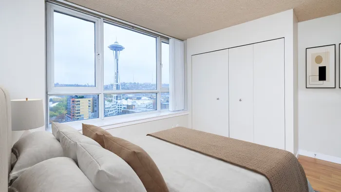 Belltown, WA, Luxury Apartments with In-Unit Washer and Dryer - Centennial Tower and Court - Bedroom with Large Windows, Oversized Closets, Wall Art, Lamp, and a Large Bed.