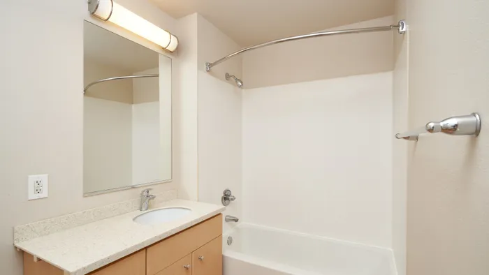 Modern bathroom with sleek fixtures, a large mirror, and built-in vanity lighting.