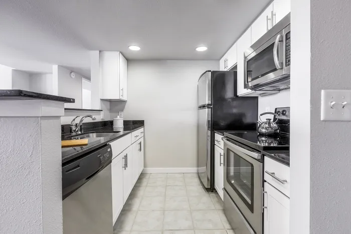 Sleek modern kitchen with stainless steel appliances, white cabinetry, and granite countertops.
