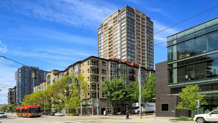 Vibrant urban scene featuring a modern apartment complex under a clear blue sky, perfectly situated in a bustling city center.