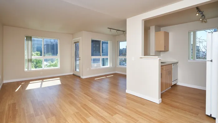 Bright, open-concept apartment with hardwood floors, natural light, and modern kitchen in an urban setting.