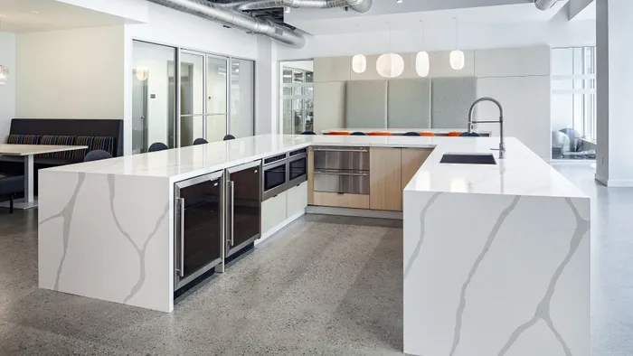 Modern kitchen with elegant white marble countertops, sleek cabinetry, and stainless steel appliances, complemented by stylish pendant lighting.