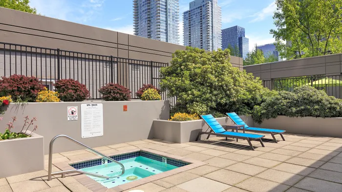 Inviting urban oasis featuring a cozy outdoor hot tub, vibrant greenery, and sleek lounge chairs against a backdrop of city skyscrapers.