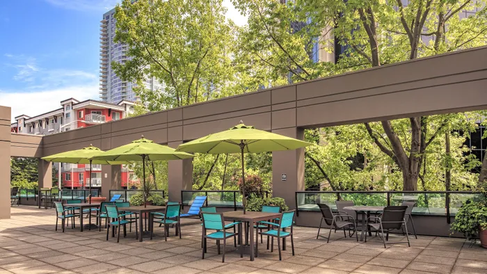 Modern patio oasis with vibrant green umbrellas, stylish seating areas, and lush greenery, perfect for relaxing and entertaining.