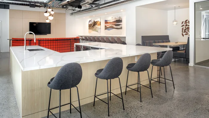 Modern kitchen and dining area featuring a sleek white island, elegant seating, and contemporary art, perfect for entertaining.