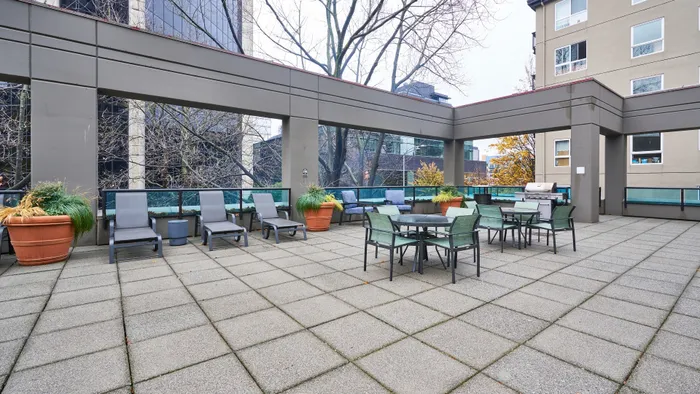Elegant outdoor terrace with stylish lounge chairs, dining area, and lush greenery, perfect for relaxation and entertaining.