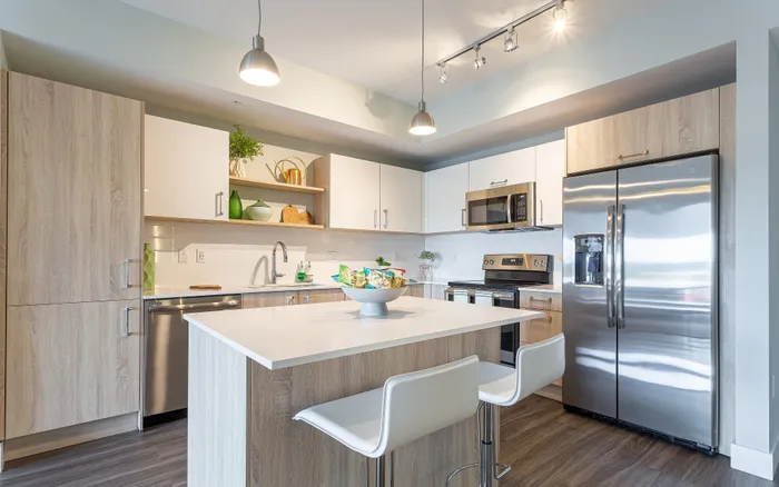 Modern kitchen with sleek stainless steel appliances, elegant wooden cabinetry, and a chic island with barstools, offering a perfect blend of style and functionality.
