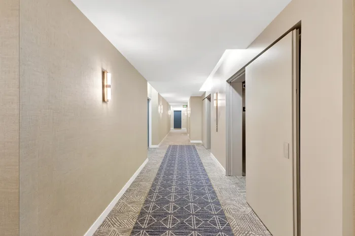 Elegant apartment corridor with stylish lighting and patterned carpets, offering a welcoming atmosphere.