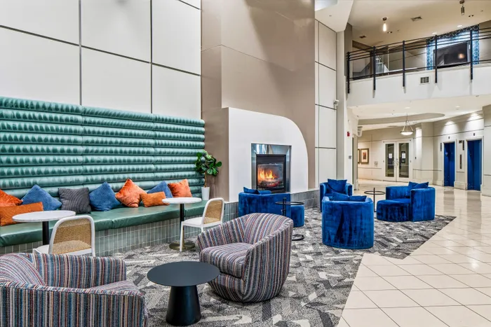Luxurious lobby with modern seating, vibrant blue chairs, and a cozy fireplace creating a welcoming atmosphere.