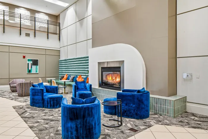 Modern lounge featuring vibrant blue seating, contemporary decor, and a cozy fireplace, ideal for relaxation and entertaining.