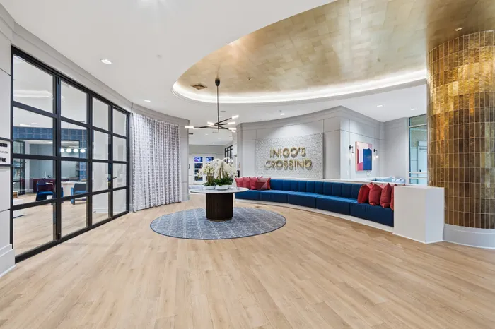 Luxurious lobby space with stylish modern design, featuring a curved blue seating area, elegant lighting, and a decorative wall displaying 'Inigo's Crossing'.