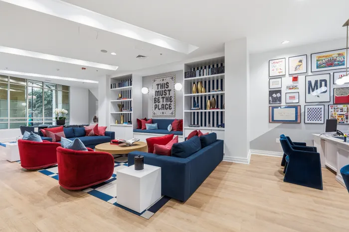 Chic and inviting lounge area with vibrant red and blue seating, modern d&eacute;cor, and artistic wall displays, perfect for relaxation and social gatherings.