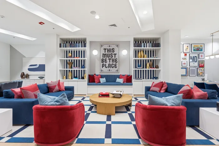 Inviting and modern living area featuring vibrant red and blue seating, stylish shelving with decorative pieces, and a cozy atmosphere perfect for relaxation.