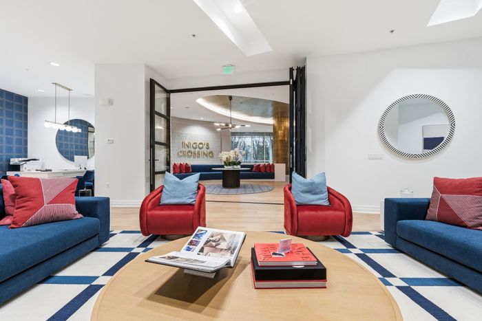 Contemporary lounge area with vibrant red and blue seating, stylish decor, and a welcoming entrance at Inigo's Crossing.