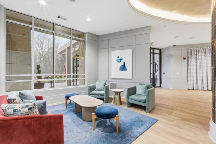 Contemporary lounge area with elegant seating, stylish decor, large windows, and natural light creating a welcoming atmosphere.