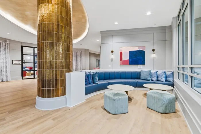 Elegant lounge area featuring a curved blue seating arrangement, golden tiled pillar, and modern art on display.
