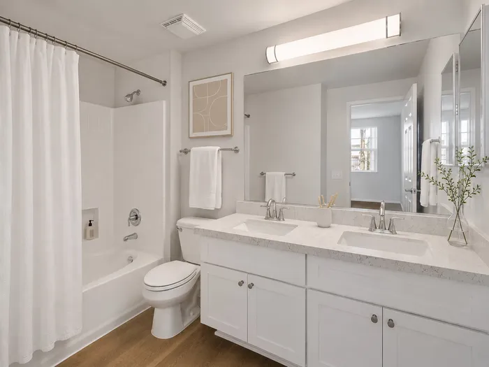 Elegant bathroom featuring a dual-sink vanity with quartz countertops, chic brushed fixtures, and a bright ambiance with natural light.