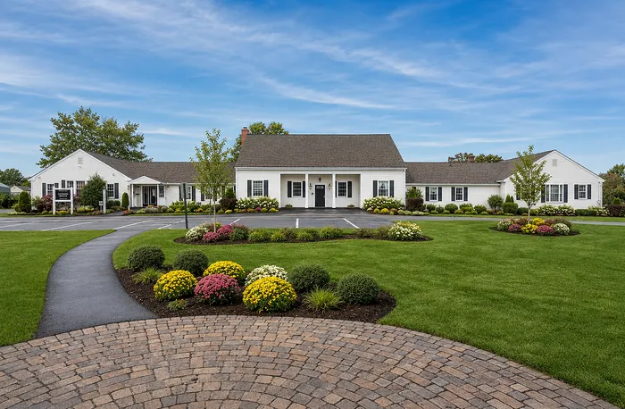 Charming residential complex with pristine landscaping and vibrant flower beds, set against a clear blue sky.