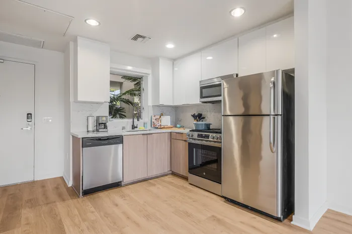 Contemporary kitchen with sleek stainless steel appliances, elegant cabinetry, and warm wood flooring enhancing a modern aesthetic.