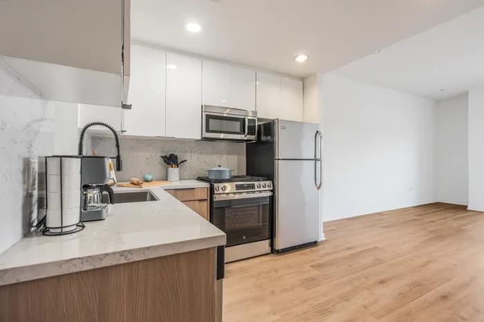 Modern kitchen with stainless steel appliances, sleek cabinetry, and elegant countertops, complemented by warm hardwood flooring.