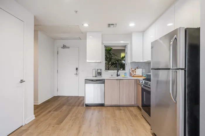 Modern kitchen with sleek stainless steel appliances, elegant light wood flooring, and ample natural light.