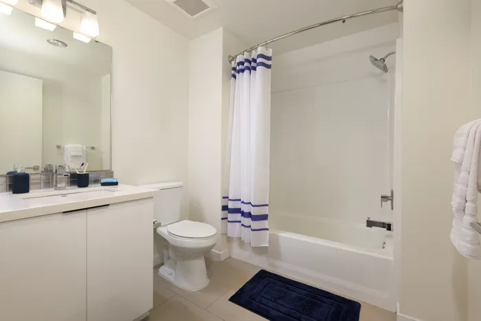 Modern bathroom with elegant white cabinetry, sleek fixtures, and a chic shower curtain adding a touch of style.