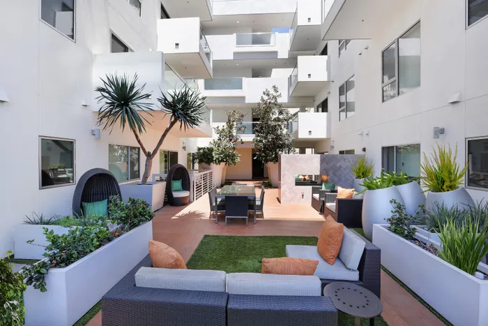 Modern apartment courtyard featuring stylish outdoor seating, lush green plants, and elegant architectural design.