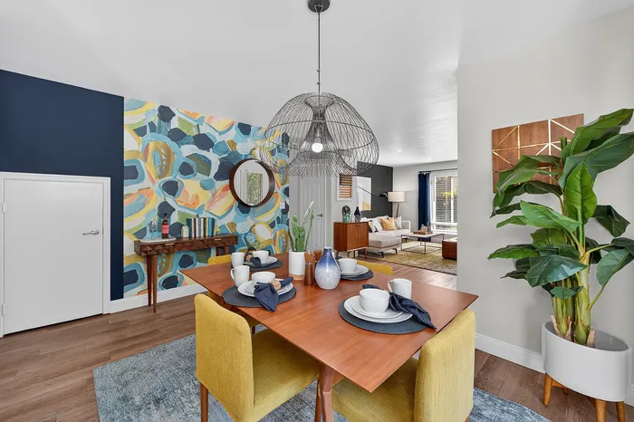 Contemporary open-plan living area with vibrant accents, featuring a chic dining table, stylish pendant light, and sunny lounge with modern decor.