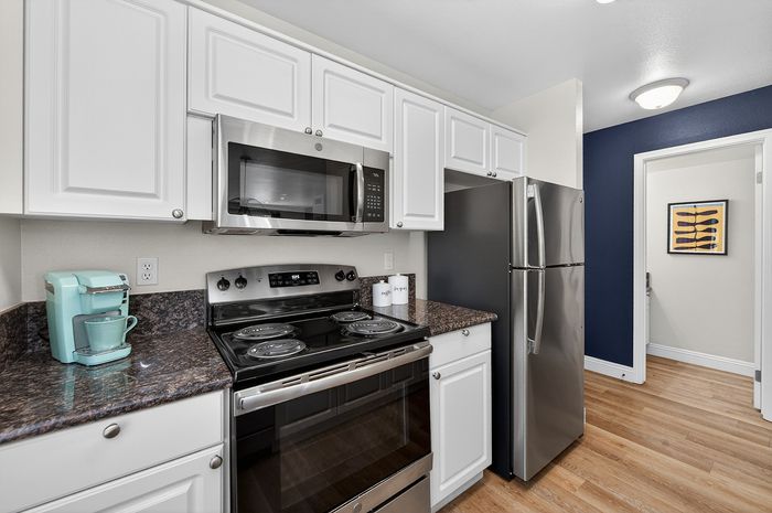 Modern kitchen with sleek stainless steel appliances, elegant white cabinetry, and stylish granite countertops.