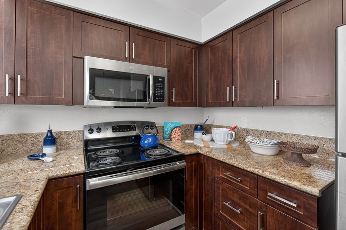 Modern kitchen with sleek stainless steel appliances, rich wood cabinets, and granite countertops, creating a warm and inviting space.