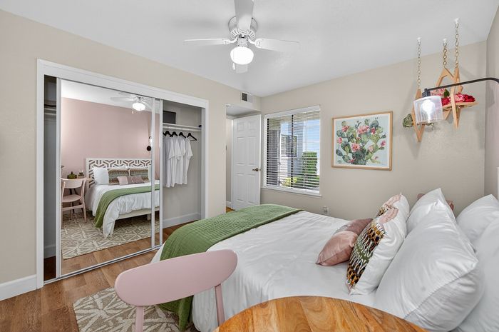 Inviting bedroom with elegant mirrored closet doors, stylish decor, and abundant natural light from a large window.