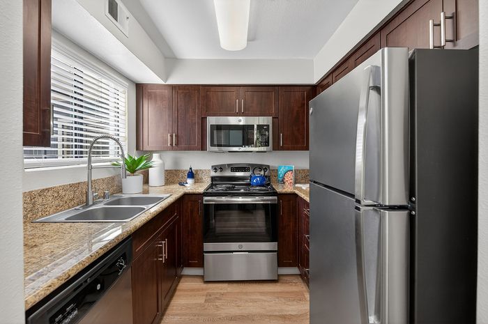 Modern kitchen with sleek stainless steel appliances, granite countertops, and rich wooden cabinetry.